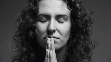 Yirmili yaşlardaki ruhani bir insan şükran duygusunu ve Tanrı 'ya olan bağlılığını gözleri kapalı ve elleri dua ederken hissediyor. Umut dolu kadın tek renkli, siyah beyaz FAITH 'e sahip.