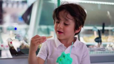 Dondurma külahını ısıran küçük çocuk, renkli bisküvinin tadını çıkaran çocuk.