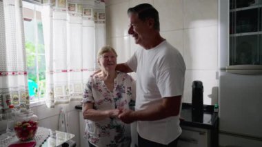 Yaşlılarla ilgilenme sahnesi. Yetişkin bir oğul, hem mutfak penceresinin yanında duran yaşlı bir anneyle iletişim kuruyor.