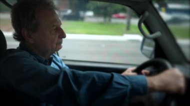 Son sınıflardan biri yolda araba kullanıyor. Beyaz tenli yaşlı bir adamın yüzü araç direksiyonunu tutuyor. 70 'lerin sürücüsü