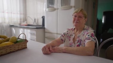 Ev mutfağında gülümseyen son sınıf kadın portresi. 80 'li yaşlarda beyaz bir kadın kameraya bakıyor. Hakiki insanlar. Ev hayatı.