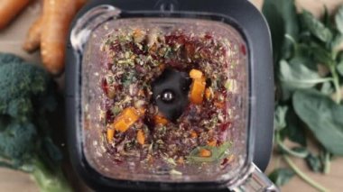 Detox içeceği için Blender 'da Ham Sebzelerin Süper Yavaş Harmanlanması, Brokoli ve havuç ve arka planda yapraklar ile üst perspektif açısı
