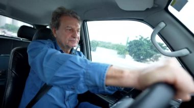 Son sınıf öğrencisi hareket halindeki arabayı kullanıyor ve içeride oturuyor. Emekli yaşlı adam yolda araba kullanıyor.