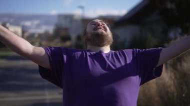 Başarılı olduğu için Tanrı 'ya şükreden mutlu bir adam. Zaferi kutlayan kişi, şükranlarını sunar. Heyecanlı şişman adam sevinçle kollarını havaya kaldırıyor.