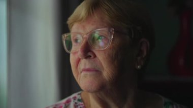 Emekli yaşlı kadın derin zihinsel bir yansımayla pencereden dışarı bakıyor. Düşünceli, düşünceli, 80 'lerinde bir kadının yakın plan yüzü.