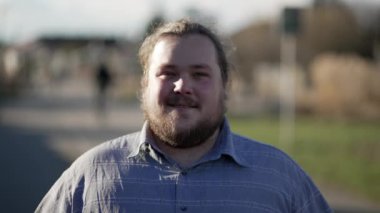 Düşünceli, genç, sıradan bir adam tefekkür ederek ileri doğru yürüyor. Mutlu, tombul bir insan, düşünceli bir ifadeyle kameraya doğru yürüyor.