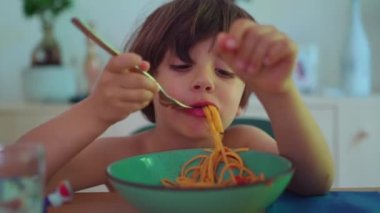 Küçük çocuk spagetti menüsünün tadını çıkarıyor. Yakından, genç adam makarna tabağının tadını çıkarıyor.