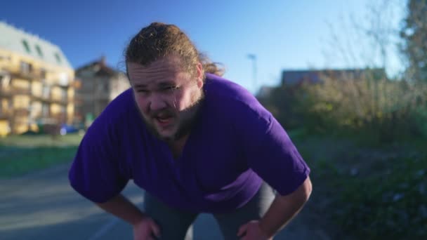 一个疲惫不堪的超重年轻人从跑步中恢复过来 过度肥胖的人深吸一口气 户外活动的生活方式 — 图库视频影像
