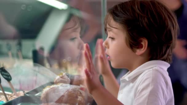デザートを味わう異なる味を見てアイスクリームのガラスカウンターにリーニング 子供時代のコンセプトを見つめる子供 — ストック動画