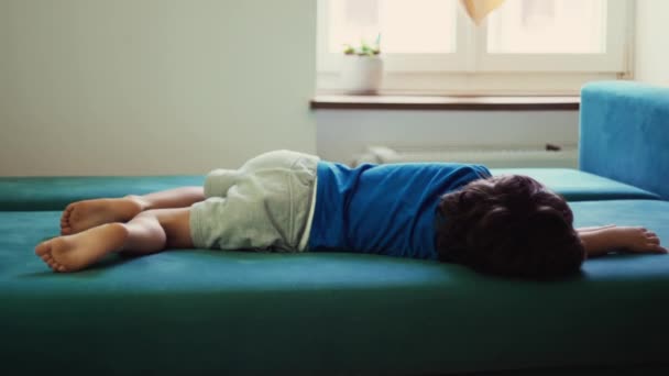 不安的小男孩躺在家里的长椅上 无精打采地感到厌烦和沮丧 — 图库视频影像