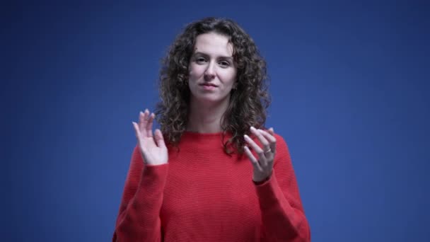 Молода Жінка Аплодує Руками Дивлячись Камеру Нейтральним Виразом Стоячи Синьому — стокове відео