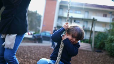 Sonbahar sezonunda halk parkında ip kaymasına tutunan bir çocuk. Gündüz vakti ip tutan çocuk.