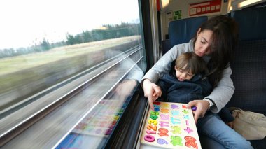 Proaktif bir anne, hızlı tren yolculuğu sırasında oğluna eğitim faaliyetlerini kolaylaştırıyor. Hareket hâlindeki çocukluk eğitimini örnek alıyor.