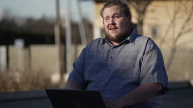 Uzaktan kumandayla çalışan mutlu bir genç adam. Düşünceli bir ifadeyle dizüstü bilgisayarla. Modern teknolojinin önünde düşünceli bir erkek.