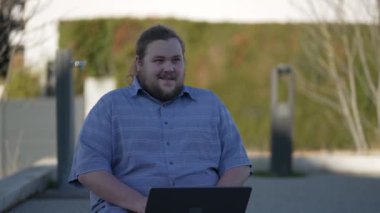 Açık havada çalışırken bilgisayarın önünde fikir üreten dalgın genç bir adam. Eureka 'da insanın dizüstü bilgisayar kullanması konsepti