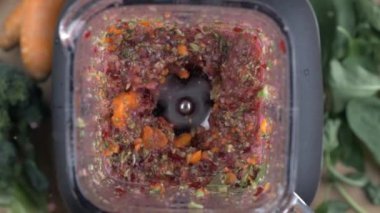 Ham sebzeleri karıştırıcının içinde hazırlamak ve DETOX içeceği yaratmak, üst görüş perspektifi