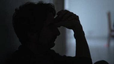 Depressed man sitting on floor. Sad unhappy person holding his forehead suffering from mental illness