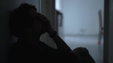 One depressed young man sitting on floor suffering from mental illness covering face with regret. Male person feeling anxious and depression