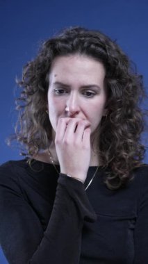 Tırnak yiyen endişeli bir kadın gelecekten endişe duyuyor. Dikey videoda takıntılı bir dürtüyle boğuşuyor.