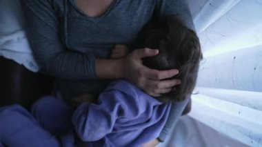 Child feeling comfortable in mother lap. Mom caresses son hair showing tenderness and love. Motherhood affection concept