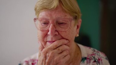 Düşünceli yaşlı kadın çözüm düşünüyor. 80 'li yaşlarda, elleri çenesinde, duyguları yakından inceleyen beyaz bir adam.