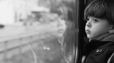 Yüksek hızlı tren ulaşımından manzaraya bakan tek renkli düşünceli bir çocuk. Düşünceli bir çocuk yolcunun siyah beyaz klipsi.