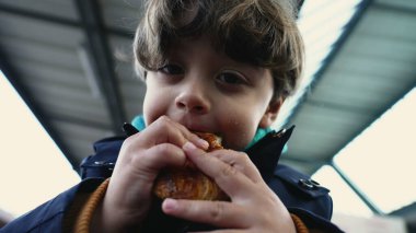 Geniş Gülümseyen Neşeli Çocuk Portresi Sonbahar Giysileri Tren Platformu 'nda Kruvasan yemek