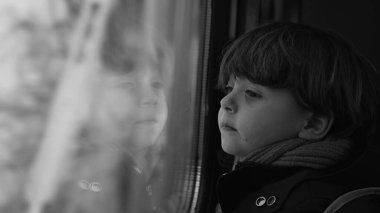 Yüksek hızlı tren ulaşımından manzaraya bakan tek renkli düşünceli bir çocuk. Düşünceli bir çocuk yolcunun siyah beyaz klipsi.