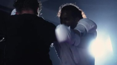 Dövüş diziyle rakibini, arka planda dramatik bir şekilde boks ringinde tekmeler. İki boksör karşı karşıya geliyor, rakibini tekmeliyor.