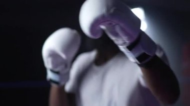 Genç bir zenci dövüşçü boks ringinin içinde kamerayı yumrukluyor. Rakibin dirseğine yumruk yemesine bakan insan portresi. Afrikalı Amerikalı sporcu