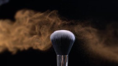 Turuncu makyaj fırçaları koyu arkaplanda ve küçük kozmetik parçacıkları, süper yavaş çekim, 1000 fps, ayrıntılar makroda birbirine dokunur