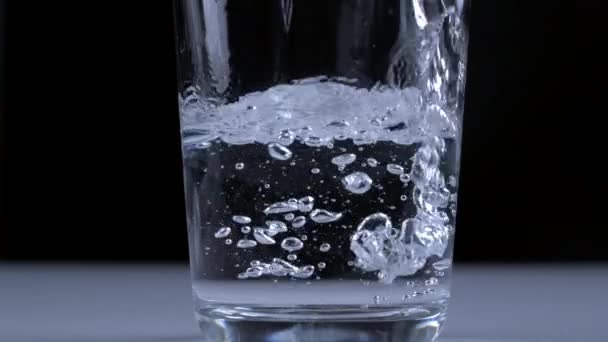 1000Fpsの極度の遅い動きのガラス透明なコップに黒い背景で注がれる水 — ストック動画