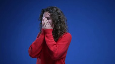 Genç ve mutlu bir kadın harika haberlere şaşırıp şok geçirir. 20 'li yaşlardaki kadın, mavi arka plandaki başarısından memnun.