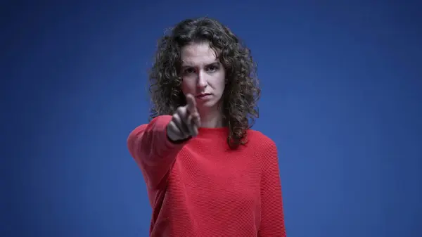 Young woman waving finger saying NO to camera refusing behavior, asserting boundary