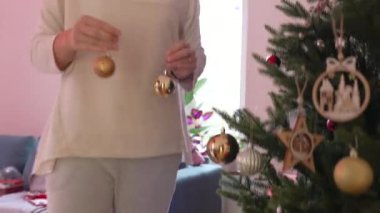 Kış tatilinde Noel ağacını süsleyen kişi. Ağaca top süsü ekleyen kadın