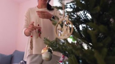 Noel ağacını süsleyen kadın kış mevsimi geleneğini kutluyor. Dekorasyon ekleyen kişinin şenlikli ruhu