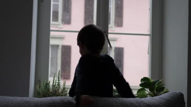 Мальчик Растягивает Тело Окном Пока Выпадает Снег Детское Утреннее Растяжение — стоковое видео