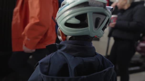 列車のプラットフォームに立っている子供の背中は 乗客が列車に乗るためにワゴン輸送から出発し ヘルメットとジャケットを着用する若い男の子 — ストック動画