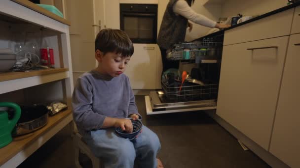 Młody Chłopiec Jagody Siedząc Kuchni Podczas Gdy Matka Wkłada Naczynia — Wideo stockowe