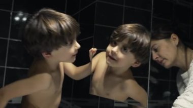 Duştan önce banyo aynasında oynayan mutlu çocuk. Evcil yaşam tarzı rutininde ayna yansımasında üstsüz şirin bir çocuk.