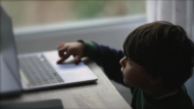 Bilgisayar ekranının önündeki çocuk. Küçük çocuk dizüstü bilgisayarı kullanıyordu. Çocuk modern teknoloji cihazı kullanıyor.