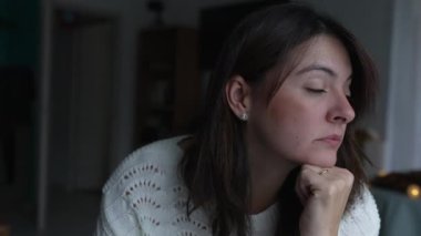 Düşünceli bir kadın evdeki sorunu derinden düşünüyor pencereden dışarı bakıyor. Yalnız başına acı çeken düşünceli bir kadının yüzünü kapat.