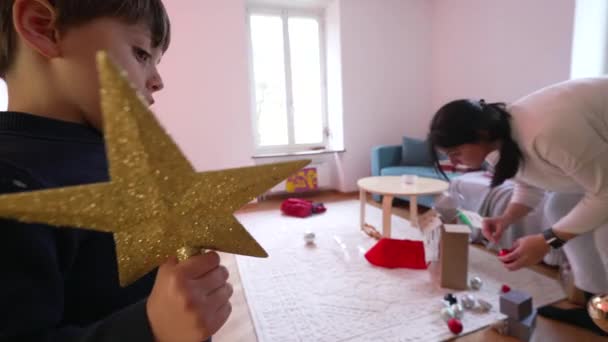 Malý Chlapec Drží Hvězdu Pohotovosti Aby Vrcholu Vánočního Stromečku Zatímco — Stock video