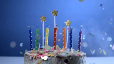 Doğum günü mumlarını mavi arka planda üfleyerek süper yavaş çekimde 1000 fps hızla, yıl dönümü kutlamalarında havada konfetiler uçuşuyor.