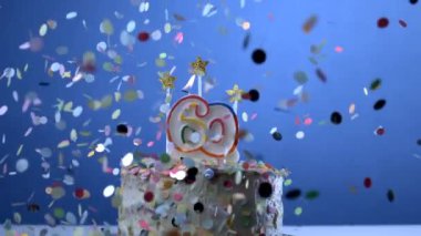 Doğum günü pastasında sembolize edilen 60 yaşındaki yaşlılığı mumlarla ağır çekimde konfetilerin düşüşü, yıldönümü kutlamaları