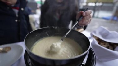 Geleneksel İsviçre fondüsünün kapanışı, insanlar kış mevsiminde Avrupa yemeklerini yiyerek açık hava restoranında peynirli ekmek yiyor.