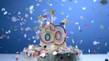 Doğum günü pastasında sembolize edilen 60 yaşındaki yaşlılığı mumlarla ağır çekimde konfetilerin düşüşü, yıldönümü kutlamaları