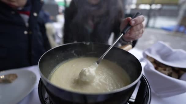 伝統的なスイスのフォンデュエを閉じ 冬の季節にヨーロッパ料理を楽しむアウトドアレストランでチーズを食べる人々 — ストック動画