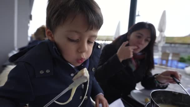 Child Blowing Hot Food While Eating Traditional Swiss Fondue Restaurant — Stock Video