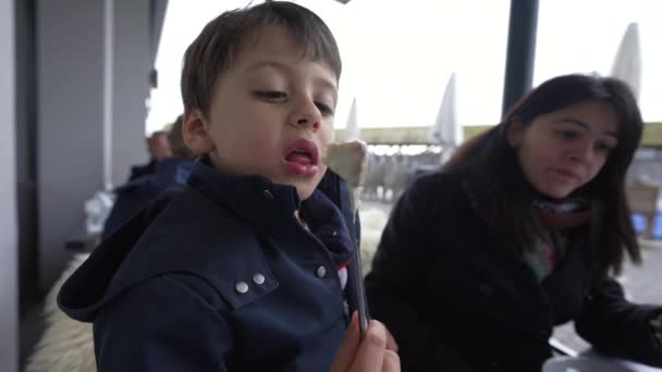 小さな男の子は母親と屋外レストランでフォンデュを食べる 冬の季節に伝統的なスイス料理を楽しむ子供のクローズアップ 家族が休暇を楽しむ — ストック動画